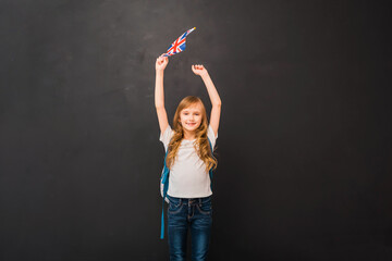 Happy child girl 8-9 y.o. holds a miniature of the English flag. Learn English Language. Education...
