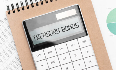 Calculator with text treasury bonds with craft colored notepad pen and financial documents.