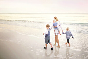 Mother and Children Walking Along Ocean Beach at Sunset