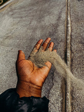 Black hand holding sand blowing in the wind