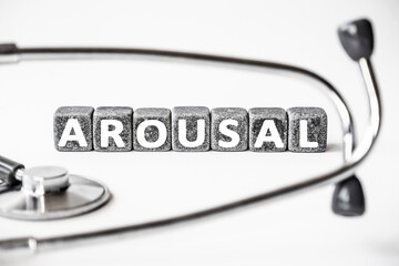 Stone block form word AROUSAL with stethoscope. White background. Medical concept. state of being...