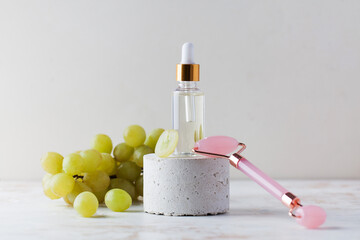Glass dropper bottle with natural grape seed oil and rose quartz facial massage roller