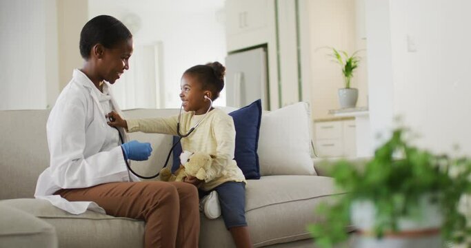 African american girl using stethoscope and smiling during medical home visit