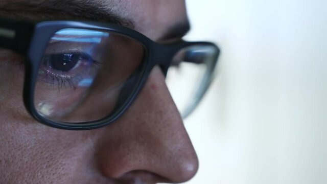 Macro on the eye of a software engineer who is working: the gaze focused on the screen,on the lens of the glasses we see the reflection.Clear and crystal clear image on the right lens. Selective focus