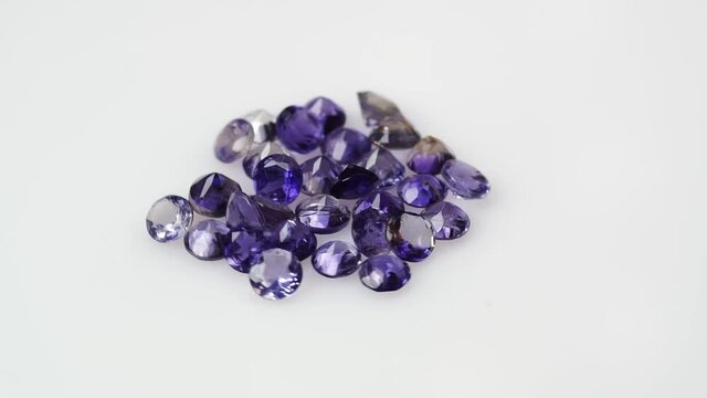 natural violet iolite gemstones on the white background on the turning table