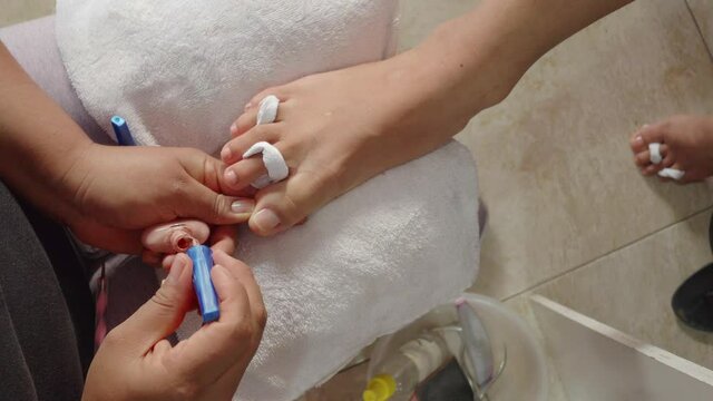 A manicure treatment, putting nail paint on the toe nails of a femal foot 