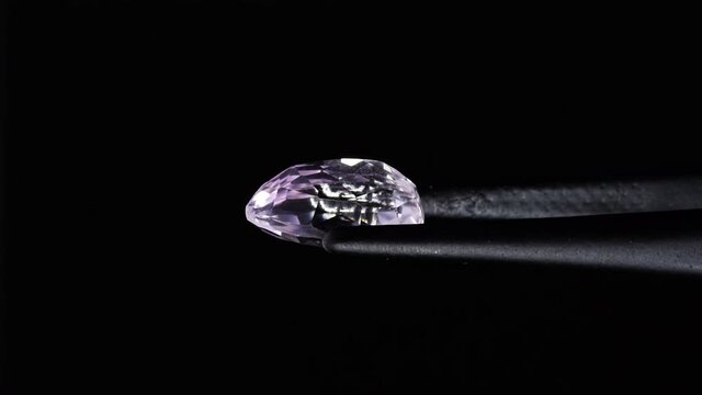 natural pink kunzite gemstone  in tweezer on the turn table