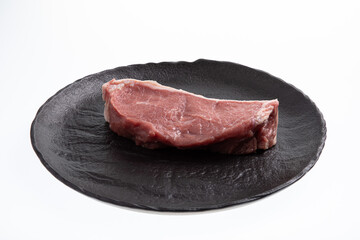 Sliced raw calf meat on black handmade plate isolated on white