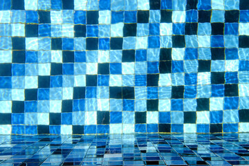 Top view of swimming pool tiled floor with the side wall through crystal clear water