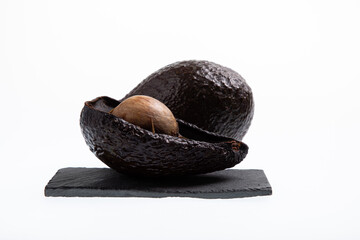 Fresh and ripe avocado next to rotting avocado cut in half with seed visible isolated on white