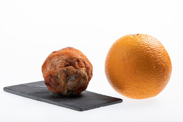Juicy fresh and ripe orange next to one rotting orange fruit isolated on white