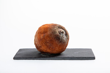 One rotting and moldy orange fruit with black and white spots isolated on white