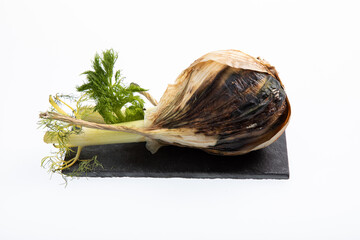 Rotting fennel bulb on black slate sheet isolated on white
