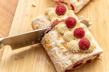 Meringue cake with raspberries cut with a knife