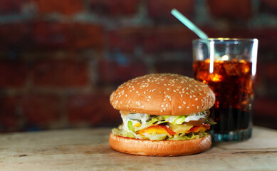 Rustic handmade hamburger and cola on a brick wall background.