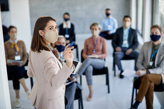 Businesswoman wearing protective face mask while giving presentation in board room.