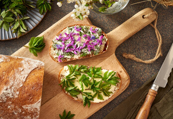 Bread with wild edible spring plants - ground elder, lungwort and purple dead-nettles, top view