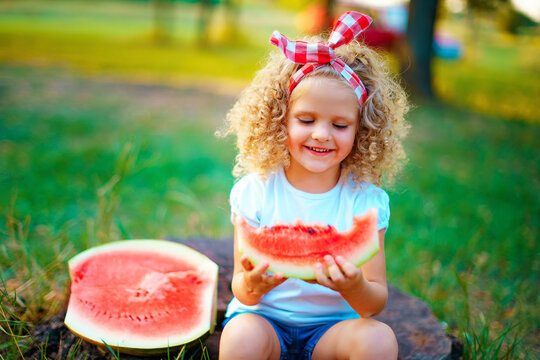 Happy Curly Child Girl Sitting On Stump And Eating Watermelon Ou