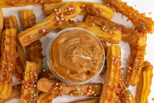 
overhead view of typical Spanish churros and container with guava arequipe covered with colored sparks