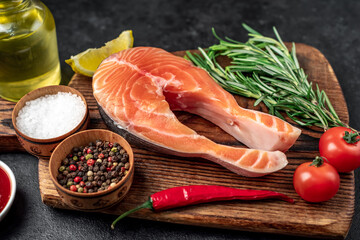 raw salmon steak with spices on a stone background