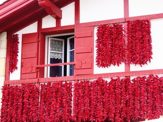 Séchage traditionnel de tresses de piments d'Espelette rouges sur la façade d’une maison du village d’Espelette, dans le pays basque (France)