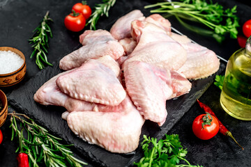 raw chicken wings with spices on a stone background