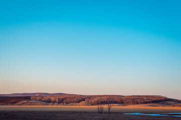 Evening sunset, field and small mountains.