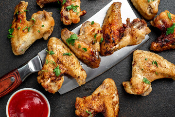 grilled chicken wings with spices on a knife on a stone background