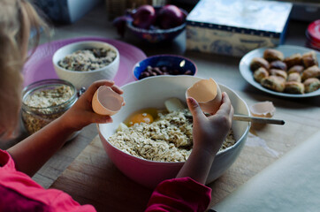 Healthy breakfast cereal with egg. Little girl prepare a dessert in a bowl. Raw ingredients for dough. Handmade food for child.