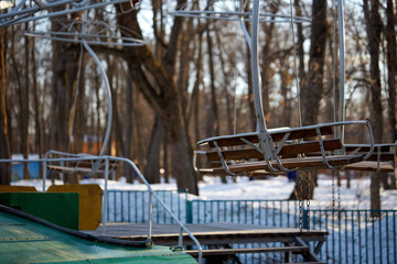 An empty swing swings on an old-fashioned amusement park carousel. Sunny day. Close-up. Selective focus