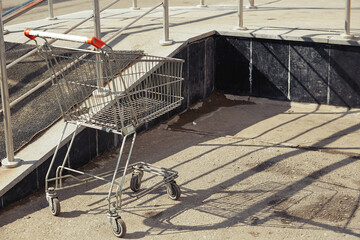 An empty supermarket shopping cart from a hypermarket is abandoned on the street.