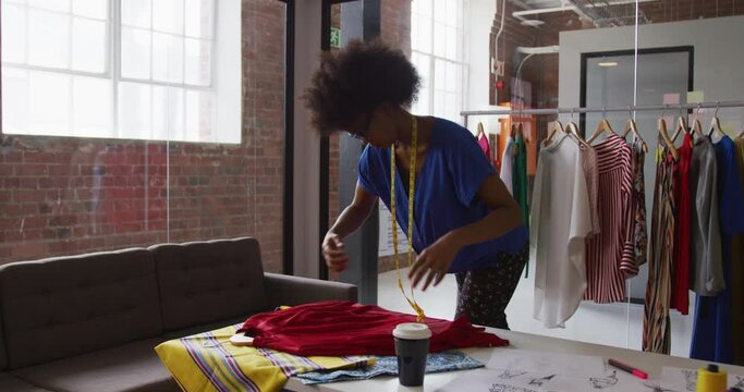 African american female fashion designer taking measurements of clothing with a tape measure