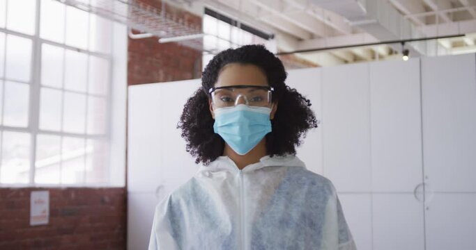 Portrait of mixed race female cleaner wearing protective face mask and overalls