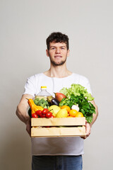 online shopping concept. A man in T-shirt holds a box of fresh food in his hands. Food delivery from the supermarket, from farmers. Delivery during quarantine