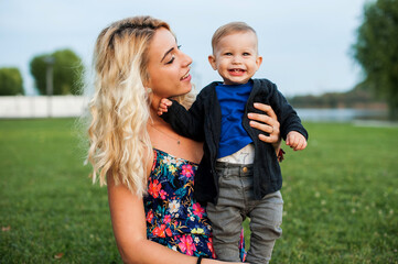 Fototapeta premium Happy mother and his little son are having fun in the park. Beautiful family is spending time together outside.