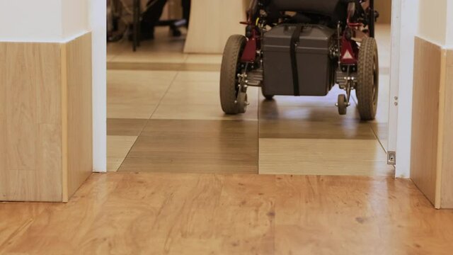 A man in a wheelchair drives down the hallway. A person with a disability moves around the hospital.