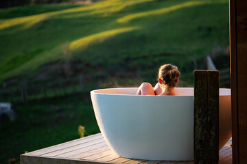 Woman in outdoor bath watching sunset