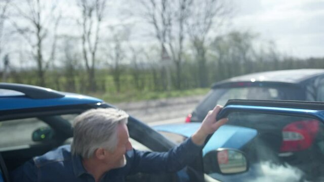 Senior Male Driver With Whiplash Injury Getting Out Of Car After Traffic Accident