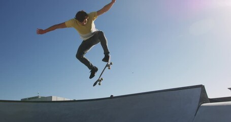 Caucasian man riding and jumping on skateboard on sunny day - Powered by Adobe