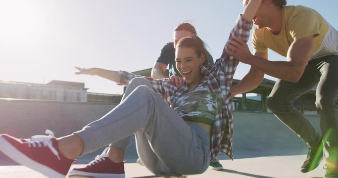 Laughing caucasian woman and two male friends, skateboarding on sunny day - Powered by Adobe