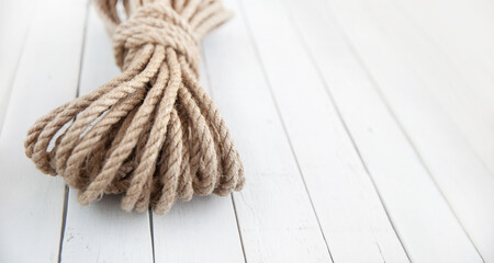 Rope made of natural jute on a white wooden background.