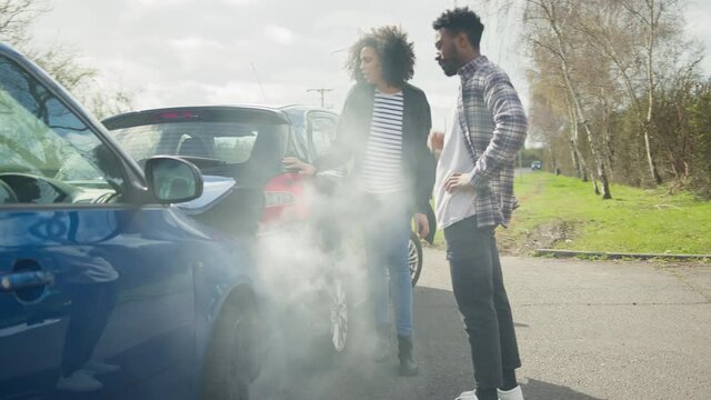 Couple Arguing Over Blame For Road Traffic Accident Standing Next To Damaged Cars