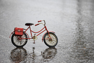 Reflection of a blurred vintage red metal bicycle in the street on a rainy day 