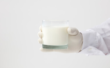 hands with glove holding glass of milk, white background