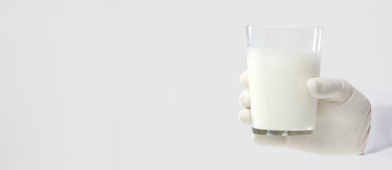 hands with glove holding glass of milk, white background