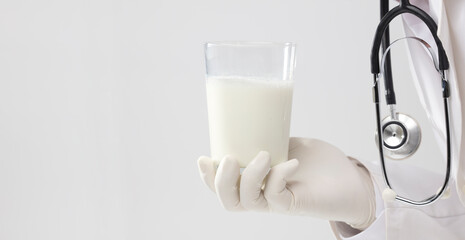 doctor with glass of milk, courtesy gesture, white background