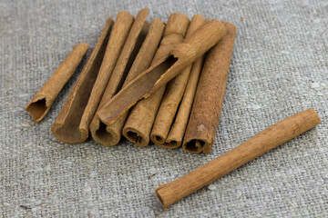 cinnamon sticks lie in bulk on a rough gray linen cloth, still life, background