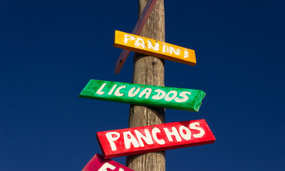 Colored signs indicating in spanish: drinks, hot dogs, sandwichs.
