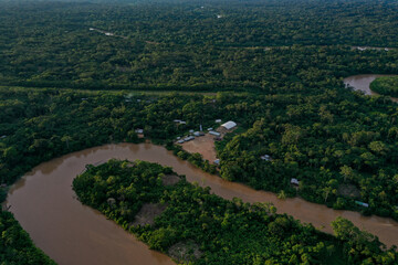 Fototapeta na wymiar Aerial view of a tropical forest canopy with a tropical river meandering through the rainforest late in the afternoon during sunset