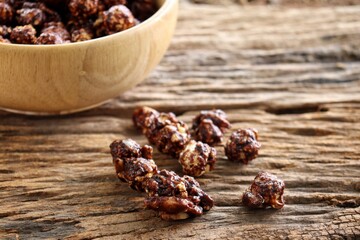 Chocolate covered popcorn on wood bowl on brown table